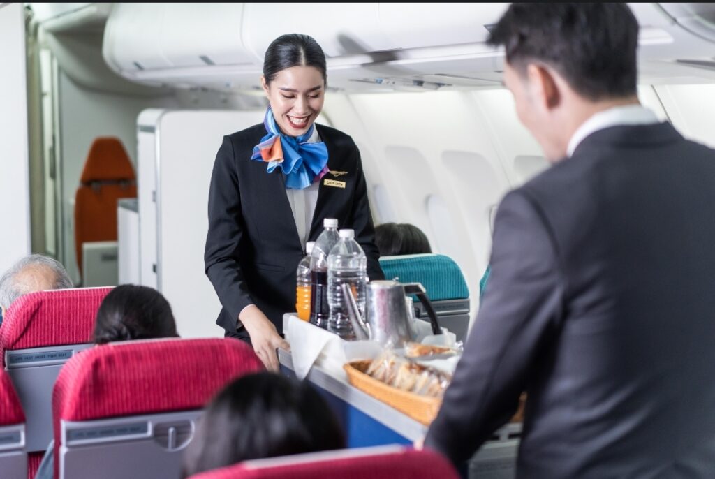 Delta flight attendant serving complimentary Biscoff cookies and Starbucks coffee in 2026.