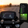 A smartphone mounted on a motorcycle handlebar displaying a successful mobile application screen for claiming vehicle insurance benefits.motorcycle insurance plan.